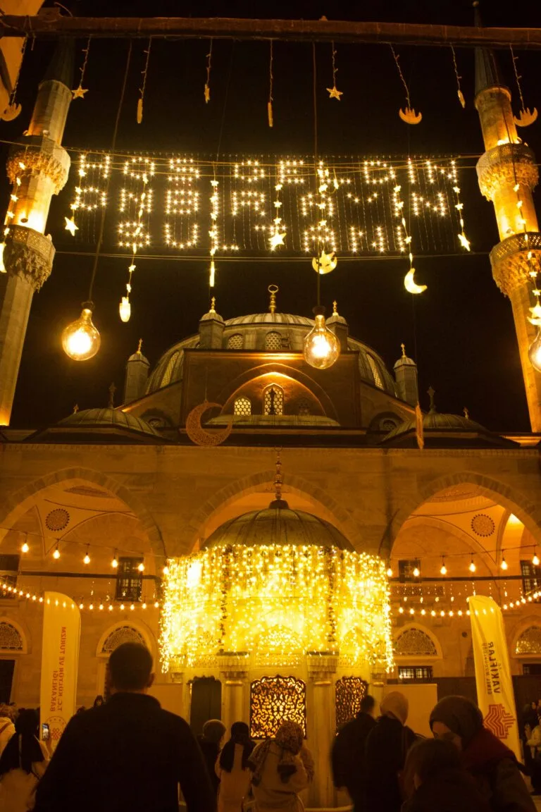 A beautifully illuminated mosque exterior decorated with lights for Ramadan celebration at night.