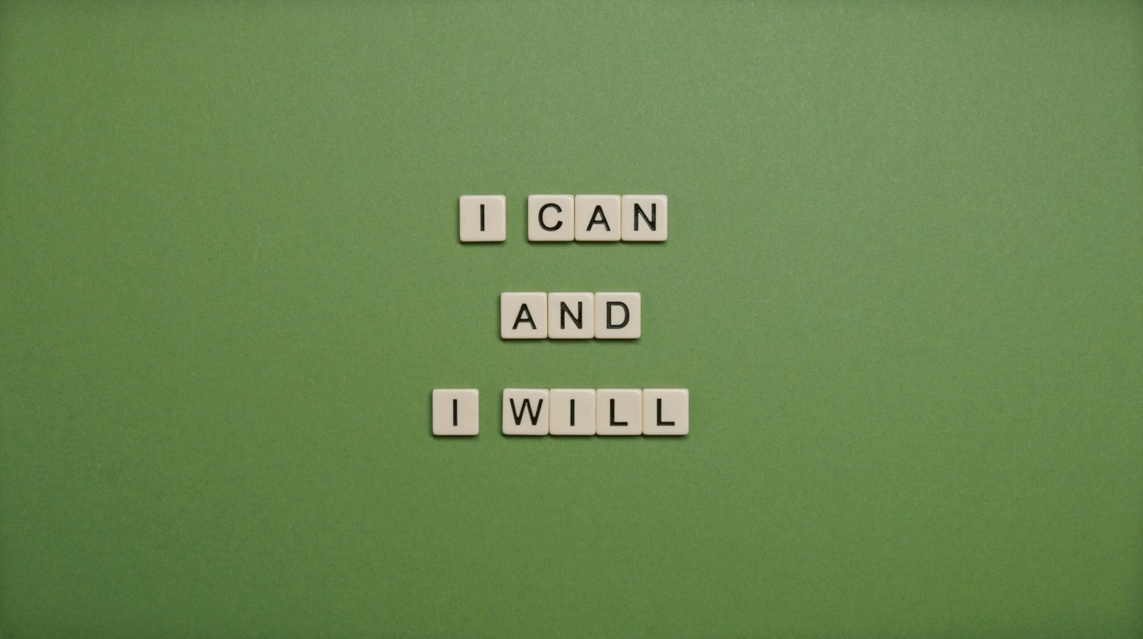 Inspirational message 'I Can and I Will' spelled with tile letters on a green background.